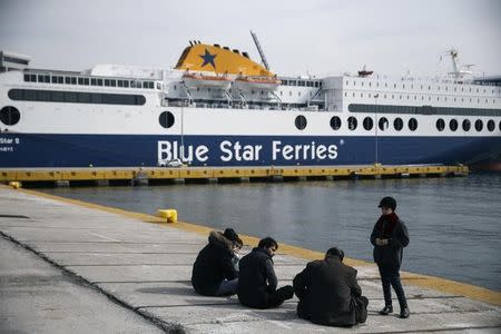 Refugees and migrants sit at a dock at the port of Piraeus, near Athens, Greece, February 8, 2016. REUTERS/Alkis Konstantinidis