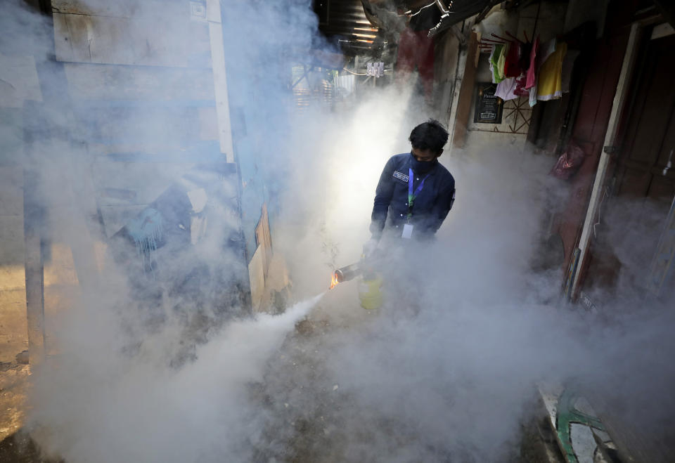 A worker fumigates a slum to prevent an outbreak of dengue fever in Jakarta, Indonesia, Wednesday, April 22, 2020. While 2019 was the worst year on record for global dengue cases, experts fear an even bigger surge is possible because their efforts to combat it were hampered by restrictions imposed in the coronavirus pandemic. (AP Photo/Dita Alangkara)