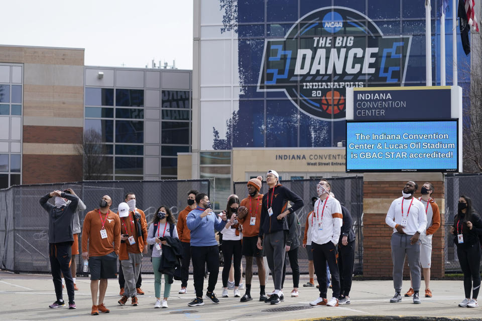 The Texas basketball team looks at the NCAA bracket for the NCAA college basketball tournament on the side of the JW Marriott building, Wednesday, March 17, 2021, in Indianapolis. (AP Photo/Darron Cummings)