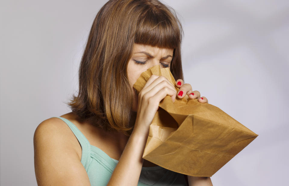 woman having a panic attack using paper bag to calm herself