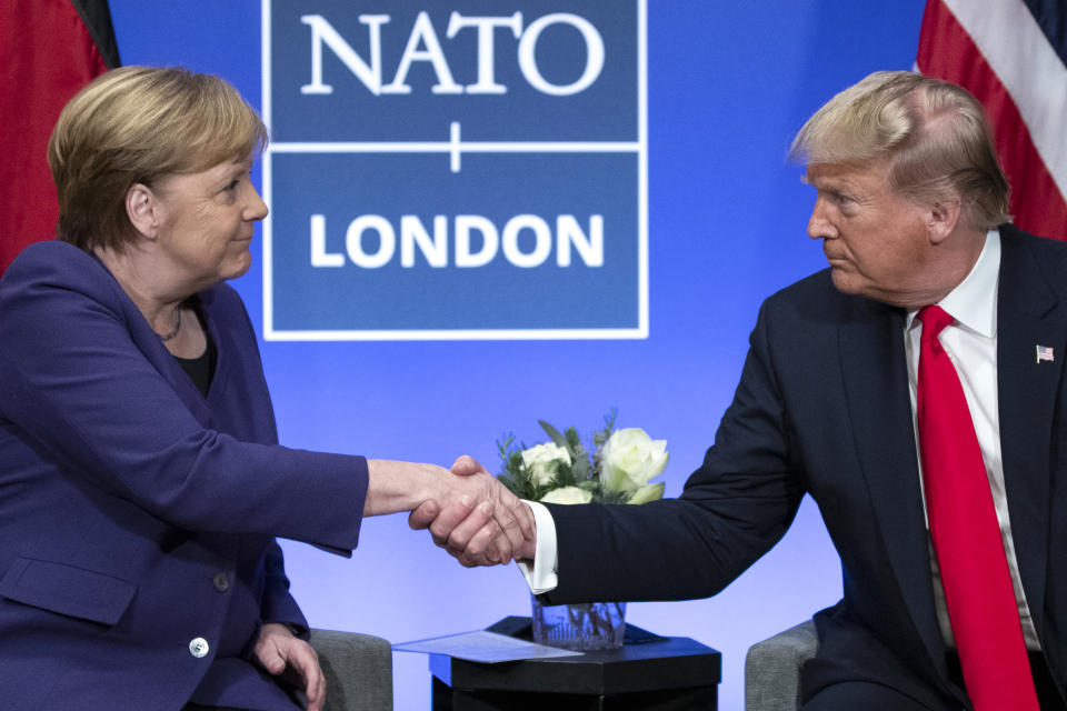 FILE - In this Wednesday, Dec. 4, 2019 file photo President Donald Trump Trump shakes hands with German Chancellor Angela Merkel during the NATO summit at The Grove in Watford, England. After more than a year of thinly veiled threats that the United States could start pulling troops out of Germany unless the country increases its defense spending to NATO standards, President Donald Trump appears to be going ahead with the hardball approach with a plan to reduce the American military presence in the country by more than 25 percent. (AP Photo/ Evan Vucci, file)