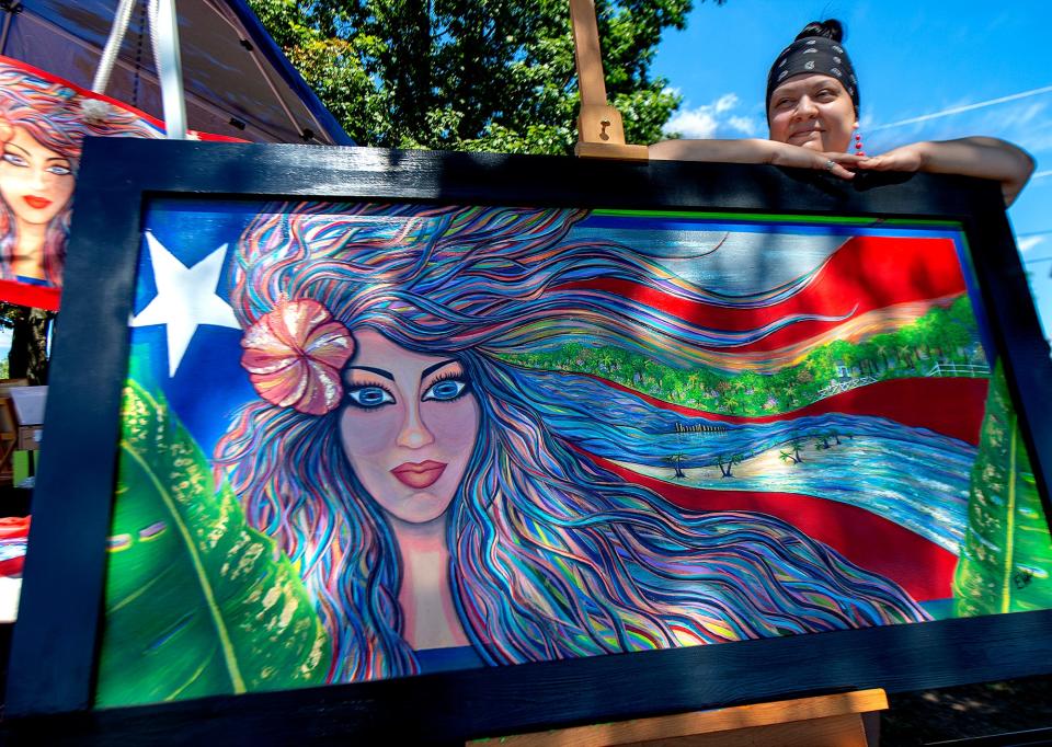 Artist, Esmeralda Aguiar, of Trenton, stands by her acrylic painting on wood, titled “Motherland,” during the 49th annual Puerto Rican Day Festival, held in Bristol Borough on Saturday, July 30, 2022.