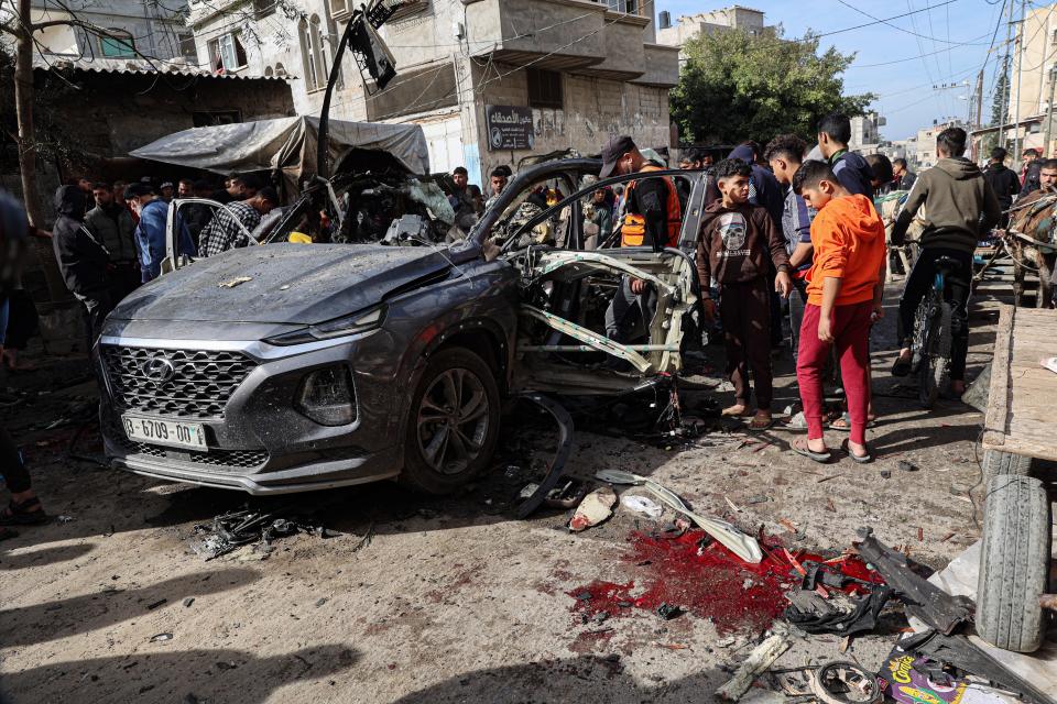 Palestinian civil defence members and onlookers gather around a car wreck following reported Israeli bombardment in Rafah in the southern Gaza Strip on January 8, 2024 amid continuing battles between Israel and the militant group Hamas.