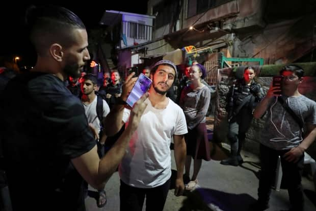 A Jewish settler and a Palestinian protester take pictures of each other with their phones on May 5 amid ongoing tension over a land-ownership dispute in the Sheikh Jarrah neighbourhood of occupied East Jerusalem. Settlers want to evict Palestinian families, claiming the land is theirs.