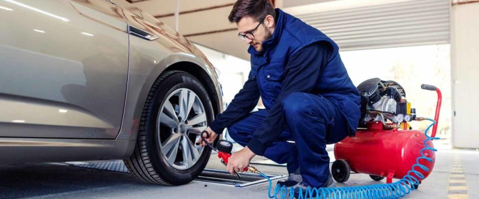 A car mechanic at the service station tries to inflate the tires