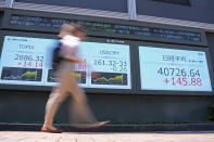 A passerby walks past an electronic stock board showing Japan's Nikkei 225 index, right, at a securities firm Thursday, July 4, 2024 in Tokyo. (AP Photo/Shuji Kajiyama)