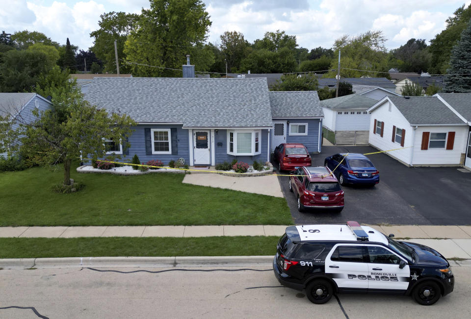 Romeoville police continue to investigate Sunday's quadruple homicide inside of a home Monday, Sept. 18, 2023, in Romeoville Ill. The home where the murders took place has two red vehicles in the driveway and is surrounded by yellow crime tape. (Stacey Wescott/Chicago Tribune via AP)