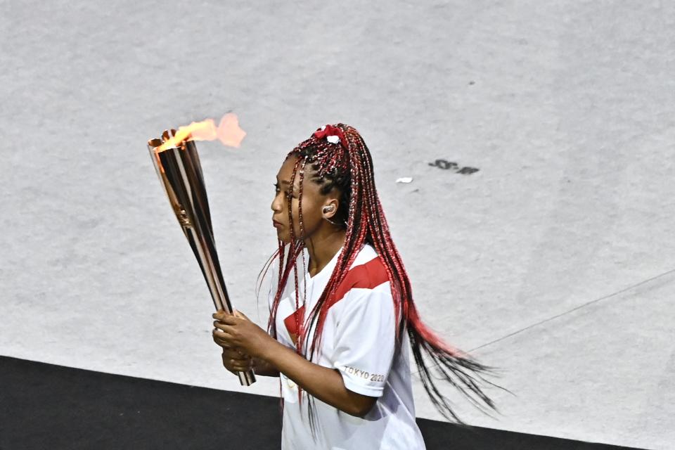 <p>Japan's tennis player Naomi Osaka carries the Olympic torch in the Olympic Stadium during the opening ceremony of the Tokyo 2020 Olympic Games, in Tokyo, on July 23, 2021. (Photo by Jeff PACHOUD / AFP) (Photo by JEFF PACHOUD/AFP via Getty Images)</p> 