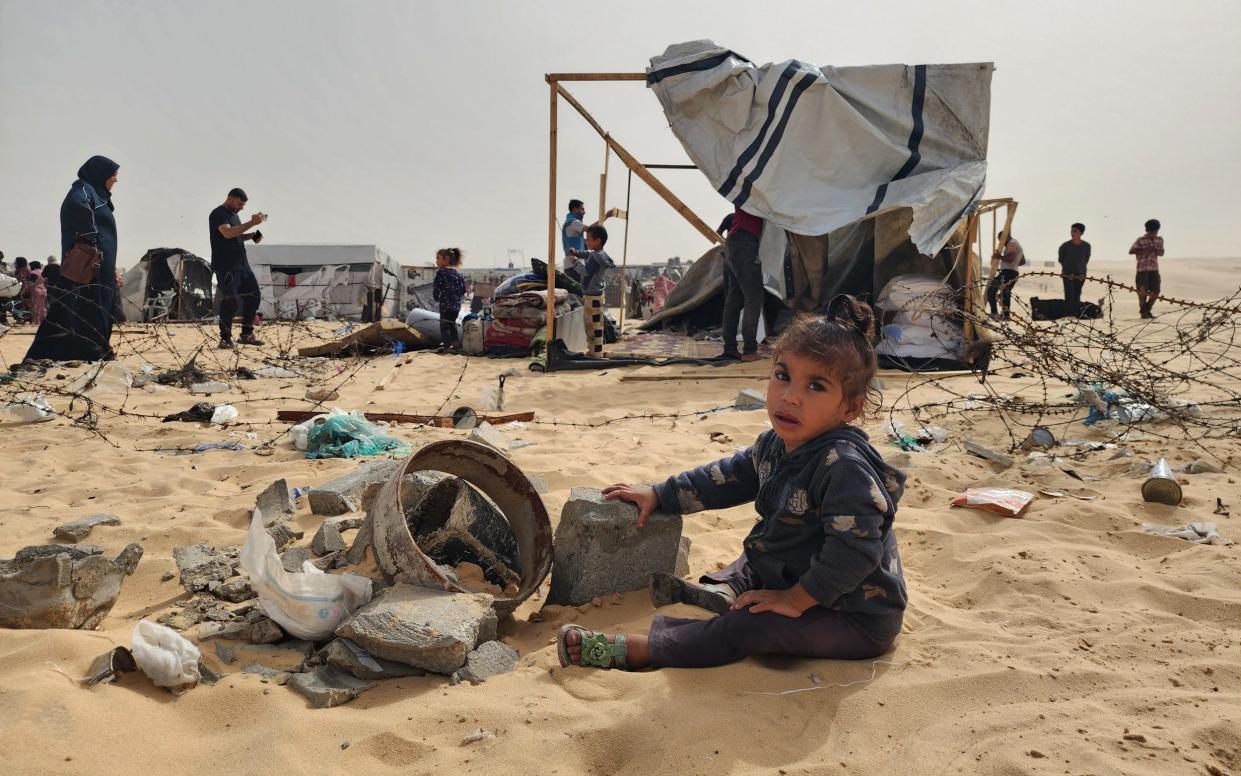 A Palestinian child plays with the rubble after Israel bombs Palestinians' tents and shelters in Rafah, Gaza