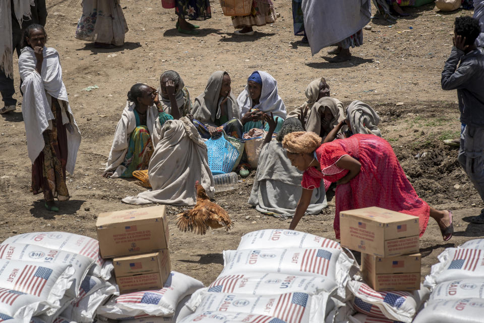 FILE - In this Saturday, May 8, 2021, file photo, a woman chases a chicken as others sit and wait to receive foodstuffs such as wheat, yellow split peas and vegetable oil at a food distribution operated by the Relief Society of Tigray in the town of Agula, in the Tigray region of northern Ethiopia. The U.N. humanitarian chief warned Friday, June 4, 2021, that famine is imminent in Ethiopia's embattled Tigray region and the country's north and there is a risk that hundreds of thousands of people or more will die. (AP Photo/Ben Curtis, File)