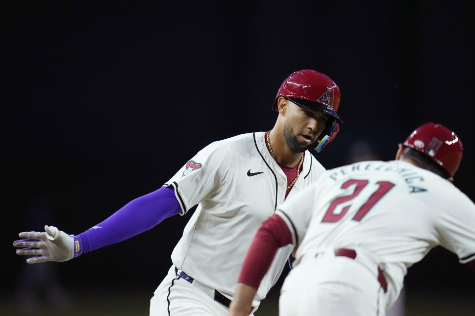 Arizona Diamondbacks' Lourdes Gurriel Jr., left, celebrates his home run against the Colorado Rockies with Diamondbacks third base coach Tony Perezchica (21) during the first inning of a baseball game Friday, March 29, 2024, in Phoenix. (AP Photo/Ross D. Franklin)