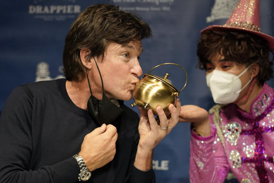 El Hombre del Año 2022 de Hasty Pudding Theatricals de la Universidad de Harvard, el actor Jason Bateman, a la izquierda, besa la caldera de pudín en una conferencia de prensa tras de recibir el premio del grupo teatral en Cambridge, Massachusetts, el jueves 3 de febrero de 2022. (Foto AP/Steven Senne)