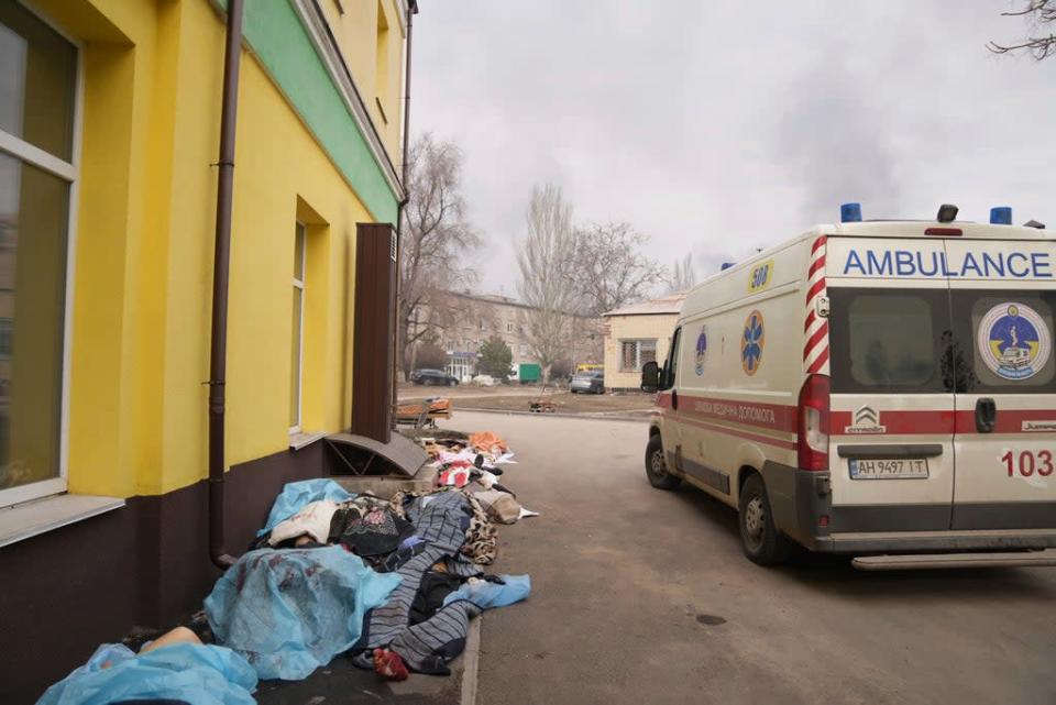 The bodies of those killed by the shelling lay covered outside a hospital in Mariupol (AP)