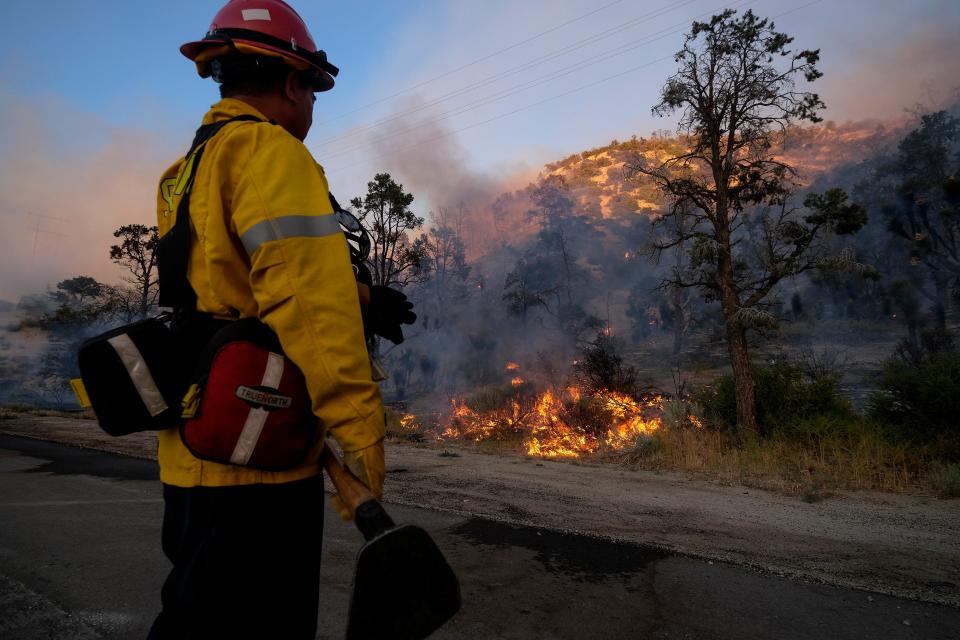 A firefighter watches as the Sheep Fire burns in Wrightwood, Calif., Sunday, June 12, 2022.