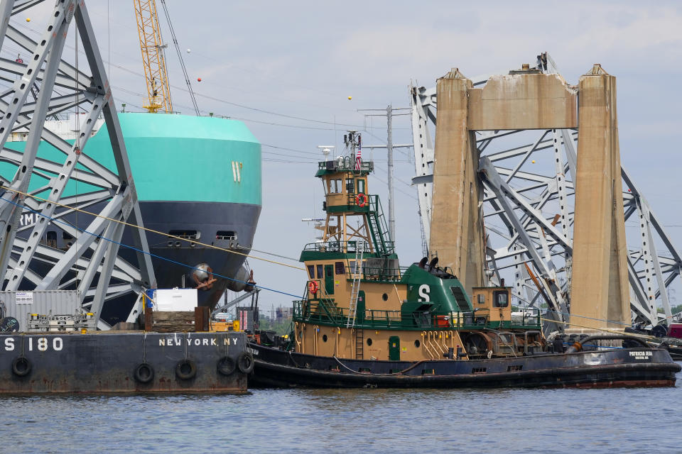 A vessel, center, moves past the stranded container ship Dali, through a newly opened deep-water channel in Baltimore after being stuck in the harbor since the Francis Scott Key Bridge collapsed four weeks ago, Thursday, April 25, 2024. (AP Photo/Matt Rourke)