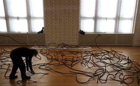 A member of museum staff makes last touches to the installation 'Forge' by Chinese artist Ai Weiwei during a media preview of the exhibition 'Evidence' at the Martin-Gropius Bau, in Berlin April 2, 2014. REUTERS/Fabrizio Bensch