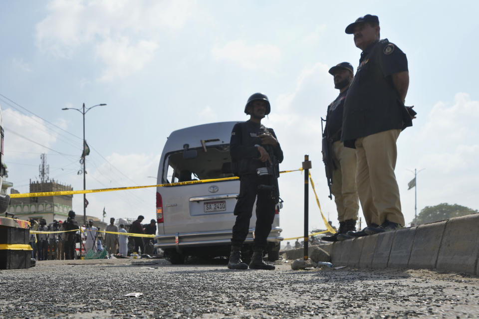 CORRECTS DATE - Police officers stand guard at the site of a suicide attack in Karachi, Pakistan, Friday, April 19, 2024. Five Japanese nationals traveling in a van narrowly escaped a suicide attack when a suicide bomber detonated his explosive-laden vest near their vehicle in Pakistan's port city of Karachi on Friday, wounding three passers-by, police said. (AP Photo/Fareed Khan)