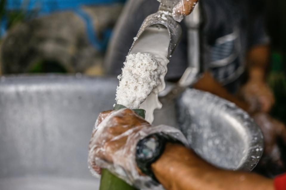 A worker at the Lemang Daun Lerek stall pouring coconut milk and glutinous rice into a bamboo tube before cooking the lemang over a fire pit in Greenwood, Batu Caves, March 31, 2023. — Picture by Hari Anggara