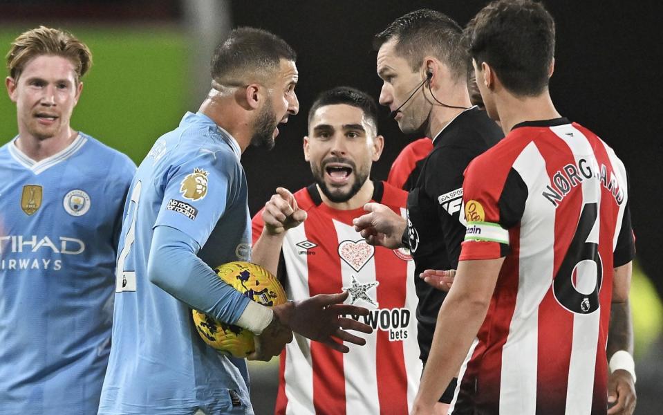 Kyle Walker of Manchester City speaks to referee Jarred Gillett as Neal Maupay of Brentford gestures