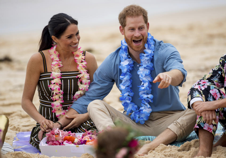 FILE - In this Friday, Oct. 19, 2018 file photo Britain's Prince Harry and Meghan, Duchess of Sussex meet with a local surfing community group, known as OneWave, raising awareness for mental health and wellbeing in a fun and engaging way at Bondi Beach in Sydney, Australia. In a stunning declaration, Britain's Prince Harry and his wife, Meghan, said they are planning "to step back" as senior members of the royal family and "work to become financially independent." A statement issued by the couple Wednesday, Jan. 8, 2020 also said they intend to "balance" their time between the U.K. and North America. (Dominic Lipinski/Pool via AP)