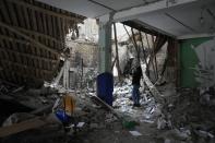 A woman takes photos of a destroyed accommodation building near a checkpoint in Brovary, outside Kyiv, Ukraine, Tuesday, March 1, 2022. Russian shelling pounded civilian targets in Ukraine's second-largest city, Kharkiv, Tuesday and a 40-mile convoy of tanks and other vehicles threatened the capital — tactics Ukraine's embattled president said were designed to force him into concessions in Europe's largest ground war in generations. (AP Photo/Efrem Lukatsky)