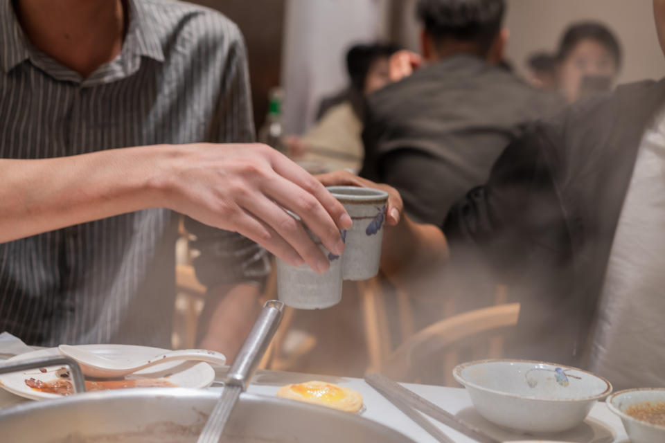 When you eat hot pot, two people hit the cup to drink, hand close-up