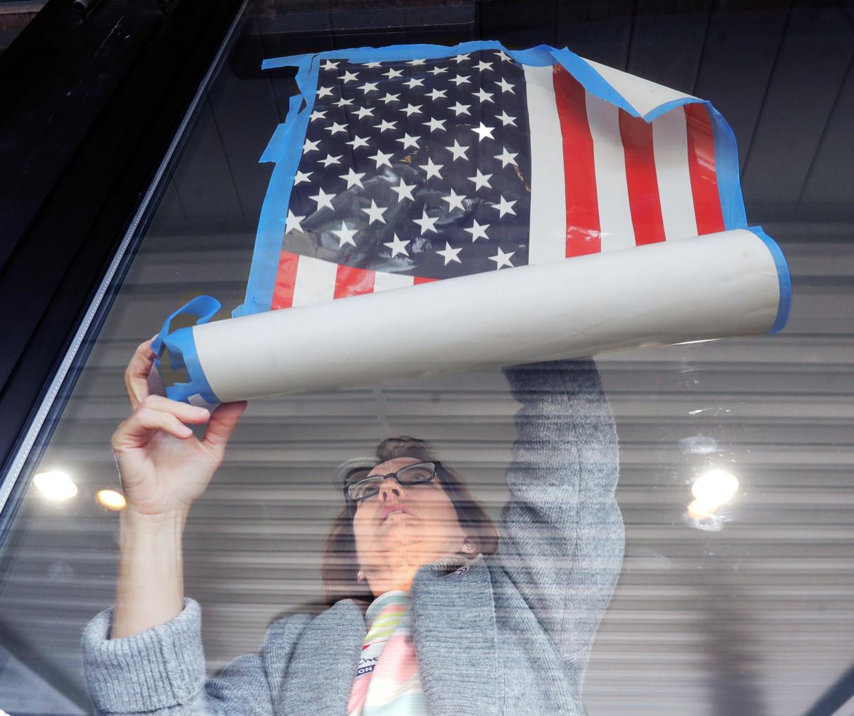 Poll worker Cheryl Deeds tapes a flag to the entrance of the Connect Church in Coventry Township on Tuesday.