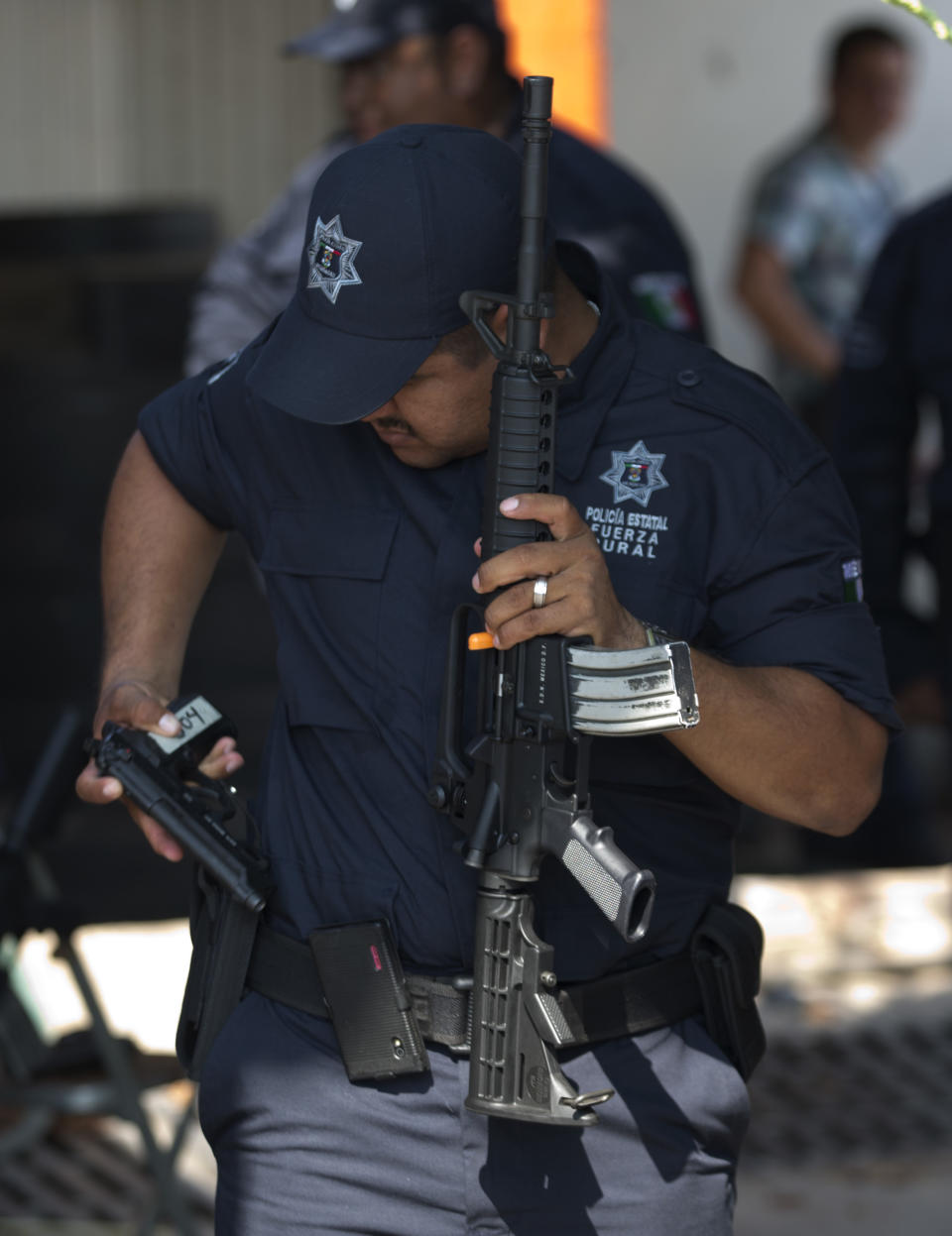 A member of a self-defense group looks at his one of newly-assigned weapons at a ceremony in Tepalcatepec, Mexico, Saturday, May 10, 2014. At the ceremony in the town where the vigilante movement began in February 2013, officials handed out new pistols, rifles and uniforms to 120 self-defense group members who were sworn into a new official rural police force. Mexico's government on Saturday began demobilizing the vigilante movement of assault-rifle-wielding ranchers and farmers that had succeeded in largely expelling the Knights Templar cartel from the western state of Michoacan when authorities couldn't. (AP Photo/Eduardo Verdugo)