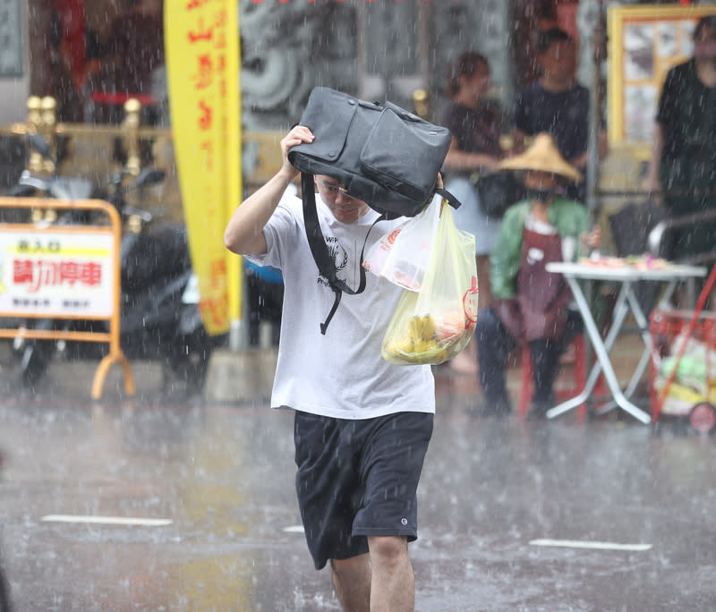 台北午後降雨  民眾以隨身物品擋雨 中央氣象署16日下午發布大雨特報，對流雲系發展旺 盛，易有短延時強降雨。圖為台北市松山區有民眾以 隨身物品遮擋雨勢、快步通過馬路。 中央社記者謝佳璋攝  113年6月16日 