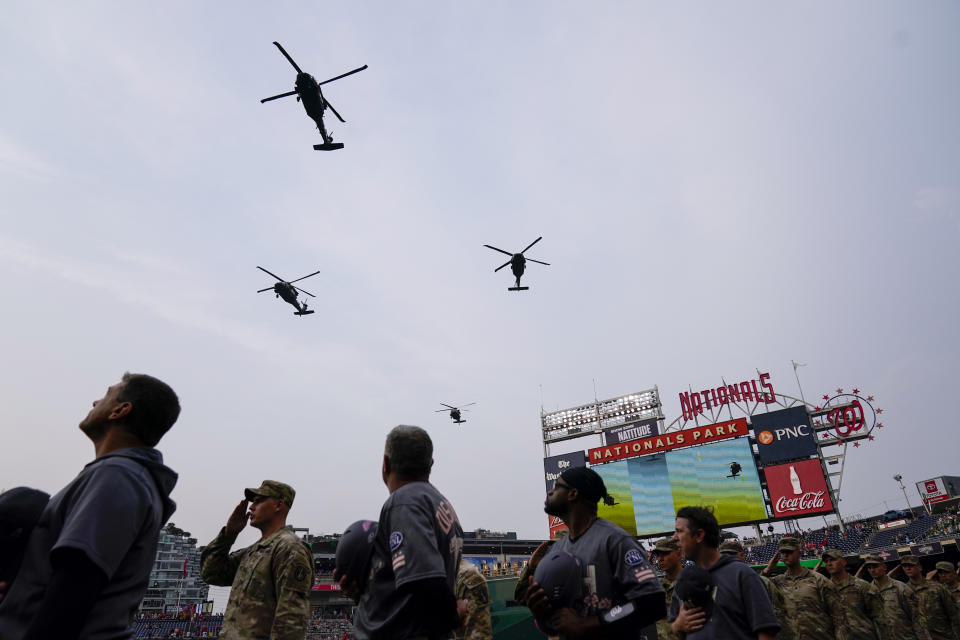 U.S. Army soldiers and members of the Washington Nationals watch a flyover by four UH-60 Blackhawk helicopters from the 12th Aviation Battalion, The Army Aviation Brigade, before a baseball game between the Nationals and the Miami Marlins at Nationals Park, Friday, June 16, 2023, in Washington. (AP Photo/Alex Brandon)