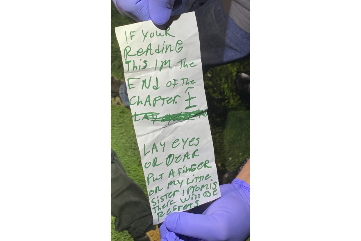A note found in the pocket of the suspect's discarded vest is examined. (AP)
