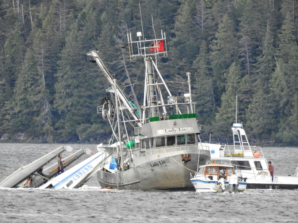 This Monday, May 20, 2019 photo provided by Aerial Leask shows good Samaritans off of fishing vessels attempting to bring in a floatplane that crashed in the harbor of Metlakatla, Alaska. Authorities say a pilot and a single passenger have died after the small plane crashed Monday near Ketchikan. (Aerial Leask via AP)