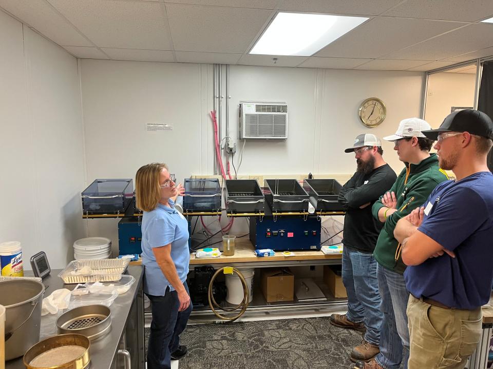 Doris Palfery, left, shows plumbing students from Fox Valley Technical College how wipes break down in slosh boxes at Kimberly-Clark's Flushability Lab in Neenah, Wisc., on Jan. 25.