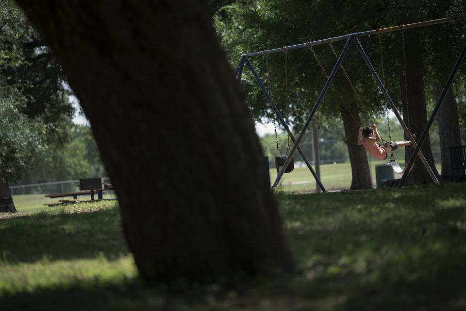 A boy plays on a swing at the Uvalde Memorial Park on Friday, May 27, 2022, in Uvalde, Texas. In a town as small as Uvalde, even those who didn't lose their own child lost someone. Some say now that closeness is both their blessing and their curse: they can lean on each other to grieve. But every single one of them is grieving. (AP Photo/Wong Maye-E)