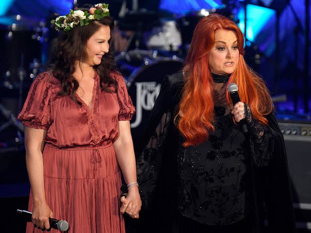<p>Mickey Bernal/Getty</p> Ashley Judd and Wynonna Judd speak onstage during Naomi Judd: 'A River Of Time' Celebration on May 15, 2022 in Nashville, Tennessee.