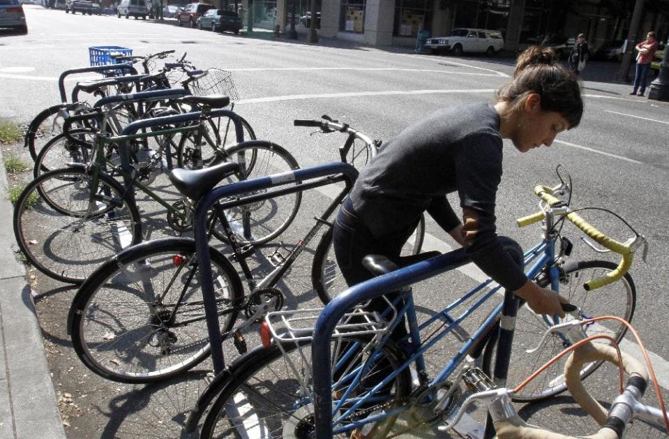 Deanna Horton locks up her bike in downtown Portland, Ore., Wednesday, Sept. 19, 2012. Researchers at Portland State University found that Portland is a magnet for the young and college educated, even though a disproportionate share of them are working in part-time jobs or positions that don’t require a college degree. (AP Photo/Don Ryan)