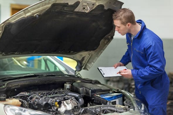 D19WW7 Mechanic with clipboard examining car engine  Mechanic; clipboard; examining; car; engine; 20s; Young; Adult; Man; Male;