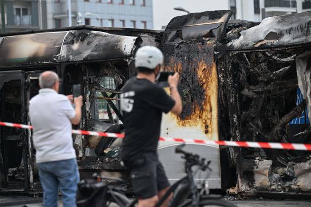 People photograph a burnt tram destroyed during protests the previous night, in Clamart, southwestern Paris, on 29 June 2023 (AFP via Getty Images)