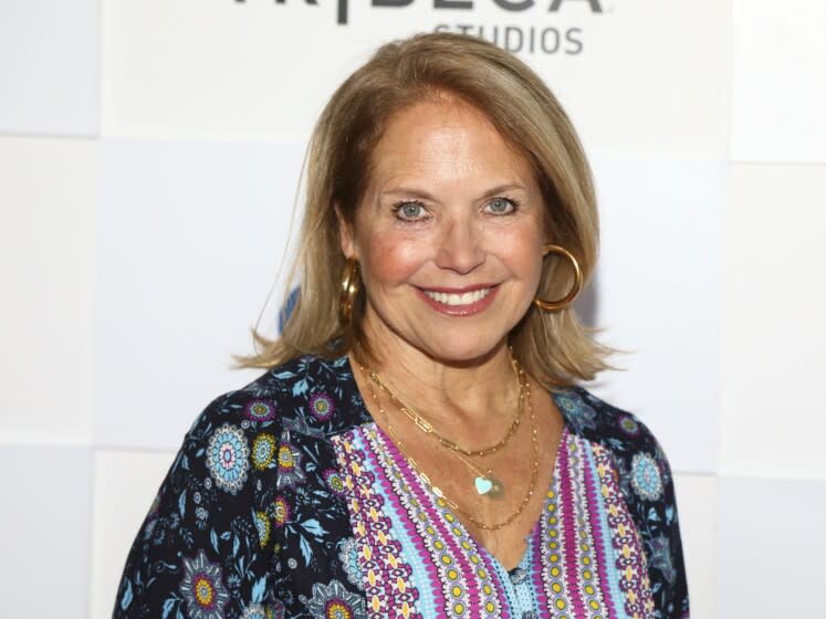 A blond woman with big hoop earrings smiles for the camera