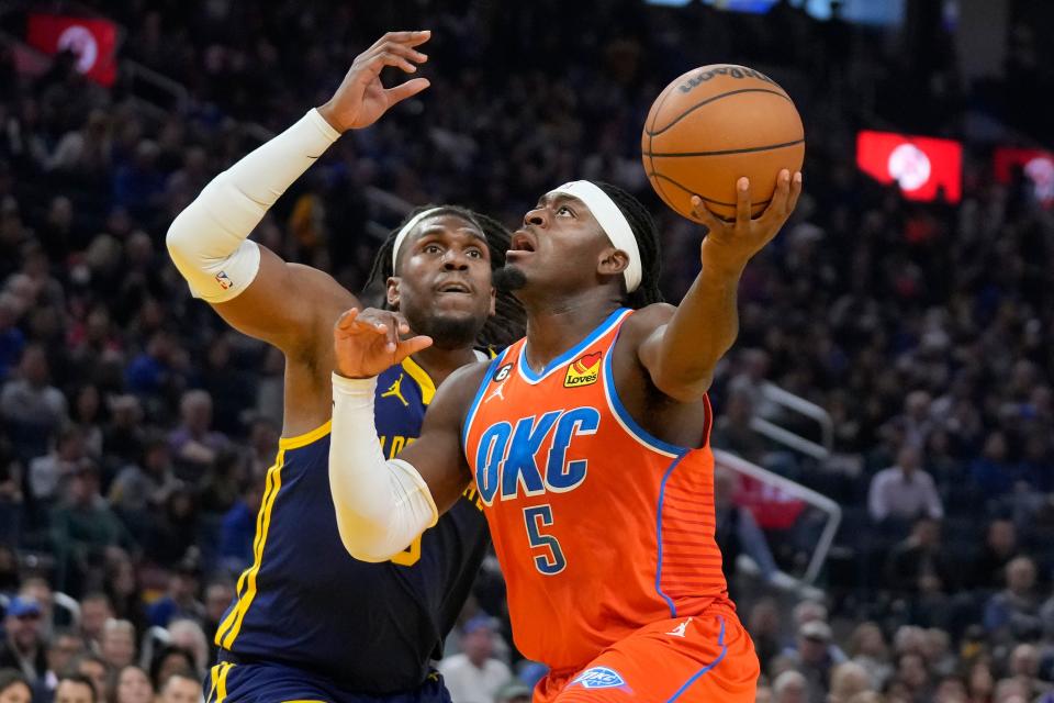 Oklahoma City Thunder guard Luguentz Dort, right, drives to the basket against Golden State Warriors forward Kevon Looney during Tuesday's game in San Francisco.