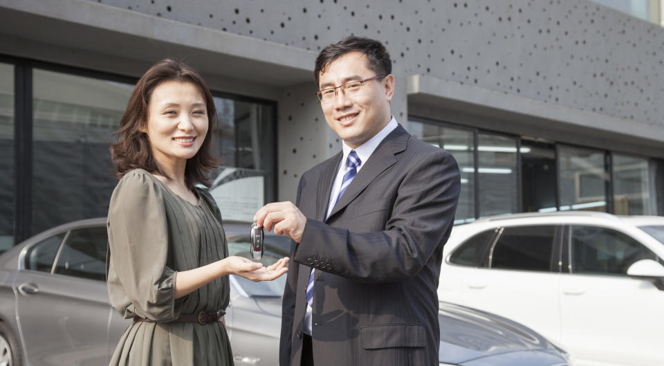 A car salesperson hands a customer the keys.