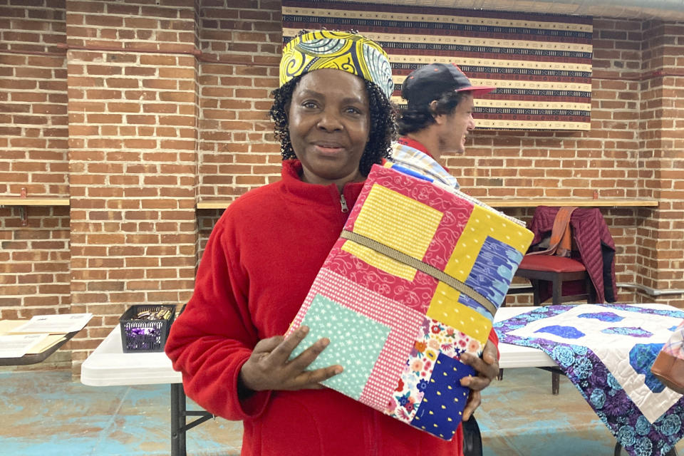 Hadijah Petro, who is originally from Congo, shows a handmade quilt she picked out for herself at a blanket giveaway for refugees and immigrants on March 21, 2023, in Burlington, Vt. The blankets were handmade by Vermont and out-of-state crafters as gifts for refugees to welcome them to the community as part of the national Welcome Blanket project. Each included a note from the crafter about her or his own family history of immigration or migration. (AP Photo/Lisa Rathke)