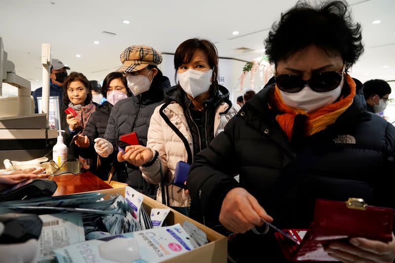 People wearing masks after the coronavirus outbreak wait in line to buy masks at a department store in Seoul