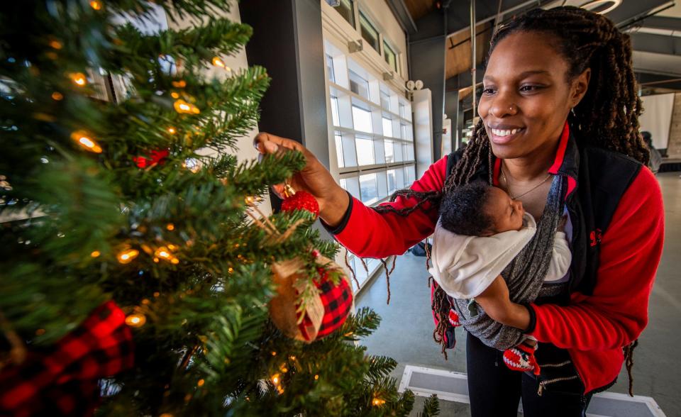 Holding Shia Moss, Shatoyia Moss helps decorate the Delta Sigma Theta Sorority, Bloomington Alumnae Chapter's Hope for the Holidays entry titled "Book Lovers." The tree is on display at Switchyard Park through Thursday.