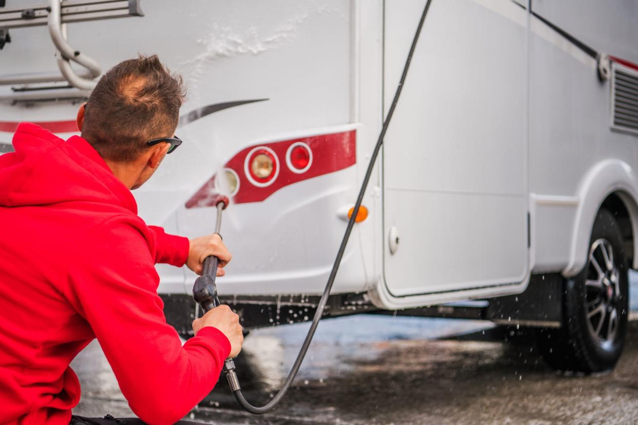 Caucasian Men in His 30s Cleaning Outside His RV Camper Van Using Pressure Washer.