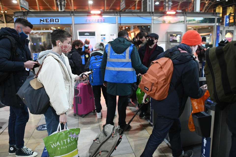 Crowds of people walk through barriers at Paddington train station in London.