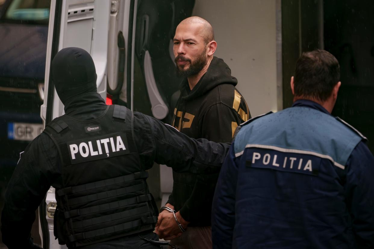Police officers escort Andrew Tate, center, handcuffed, to the Court of Appeal in Bucharest, Romania, Tuesday, March 12, 2024. Online influencer Andrew Tate was detained in Romania and handed an arrest warrant issued by British authorities, his spokesperson said Tuesday.