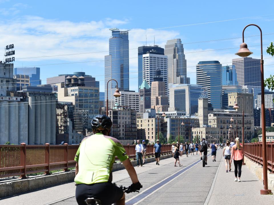 People biking and walking across the Stone Arch Bridge in Minneapolis.