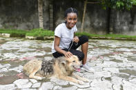 In this photo taken on Wednesday, Oct. 14, 2020, Dodeye Ewa, 16 year play with a dog outside her compound in Calabar, Nigeria. The third child is bothered by President Donald Trump's rhetoric and his policies toward international students, most recently one announced Friday that limits their stays in the U.S. to two or four years with uncertainty about whether their visas will be extended. (AP Photo/Daniel H Williams )