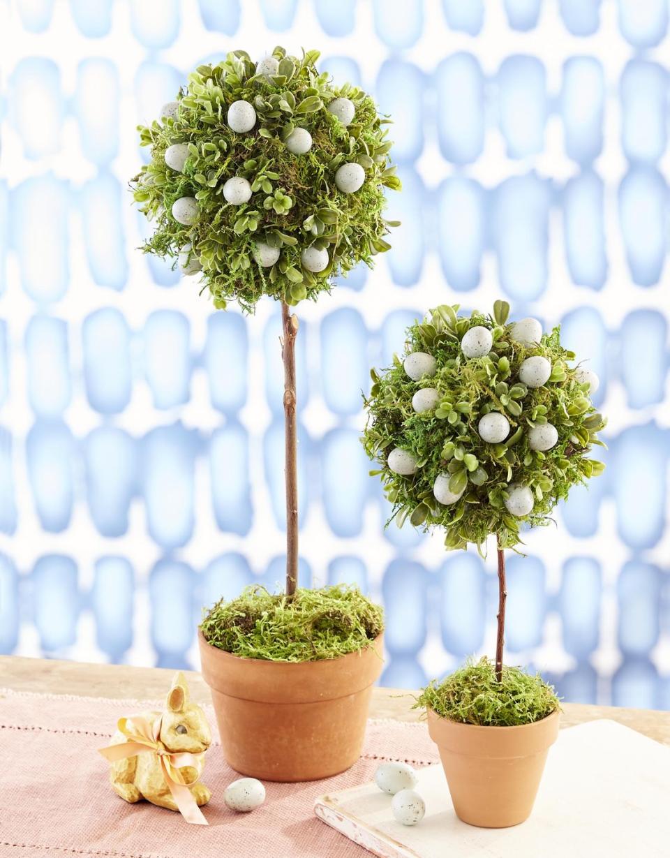 <p>Made from moss and faux boxwood, these topiaries make the perfect focal point for your Easter table.</p><p><strong>T</strong><strong><strong>o make:</strong></strong> Using hot-glue, attach preserved green sheet moss and fake mini boxwood greenery to a round Styrofoam ball until covered. Nestle faux robin’s eggs in moss, attaching with glue. Fill a clay pot with floral foam. Poke a stick into bottom of topiary, and insert into floral foam; cover foam with moss.</p><p><a class="link " href="https://www.amazon.com/Creative-Co-op-HD4474-Speckled-Ceramic/dp/B0014BUL6M/ref=sr_1_2?tag=syn-yahoo-20&ascsubtag=%5Bartid%7C10050.g.1111%5Bsrc%7Cyahoo-us" rel="nofollow noopener" target="_blank" data-ylk="slk:SHOP FAUX EGGS;elm:context_link;itc:0;sec:content-canvas">SHOP FAUX EGGS</a></p>